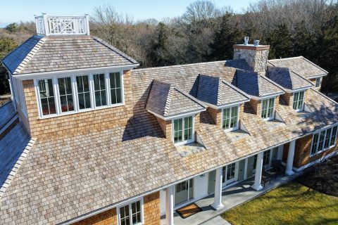 Complex cedar roof with multiple dormers and architectural details